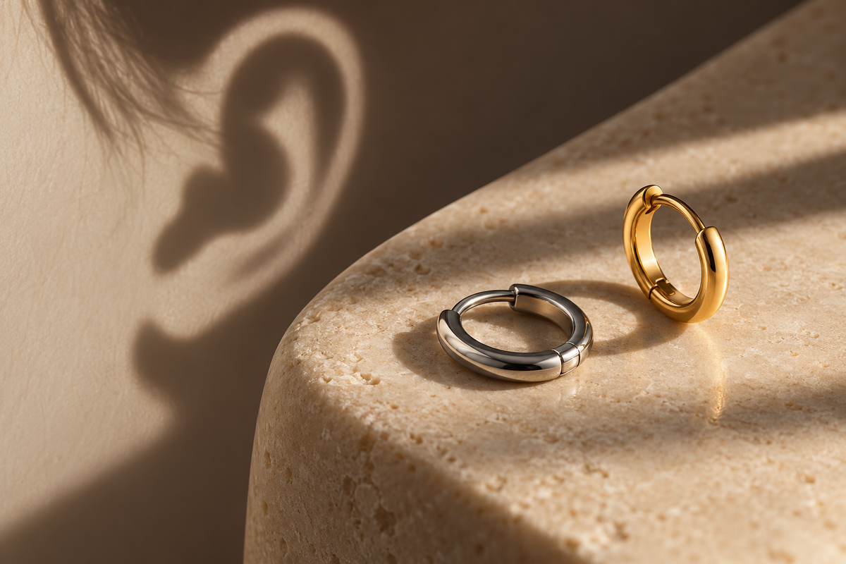 AI illustration of silver-tone and gold-tone hinged hoops on warm stone